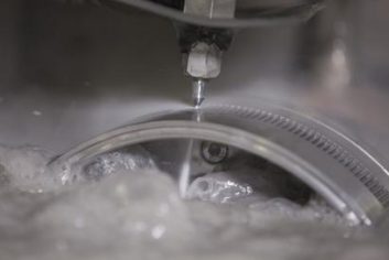 Gros plan sur une machine de découpe jet d'eau réalisant une précision extrême sur une pièce métallique en milieu humide.