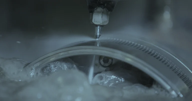 Gros plan sur une machine de découpe jet d'eau réalisant une précision extrême sur une pièce métallique en milieu humide.
